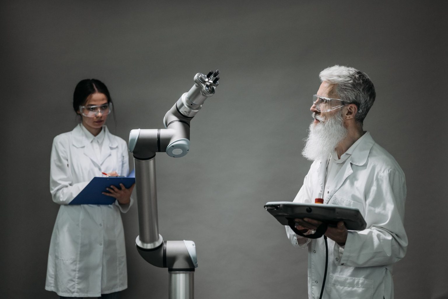 Dois cientistas trabalham com um braço robótico em um laboratório de tecnologia.