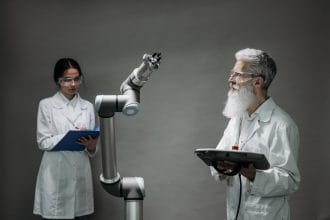 Dois cientistas trabalham com um braço robótico em um laboratório de tecnologia.