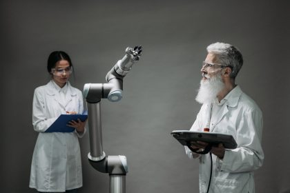 Dois cientistas trabalham com um braço robótico em um laboratório de tecnologia.