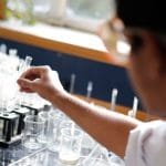 Estudante realiza um experimento de química com tubos de ensaio em um laboratório.
