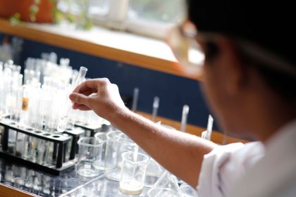 Estudante realiza um experimento de química com tubos de ensaio em um laboratório.