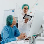 Duas pesquisadoras conversam e analisam informações em um tablet dentro de um laboratório.