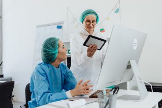Duas pesquisadoras conversam e analisam informações em um tablet dentro de um laboratório.