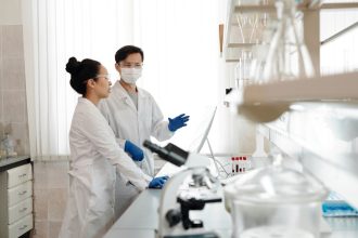 Cientistas usando equipamentos de proteção discutem experimentos em um laboratório.